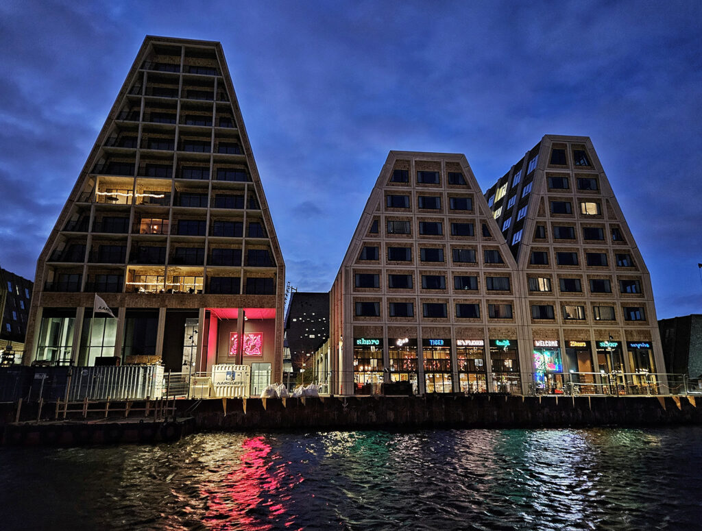 exterior of a hotel with neon lights by the waterside